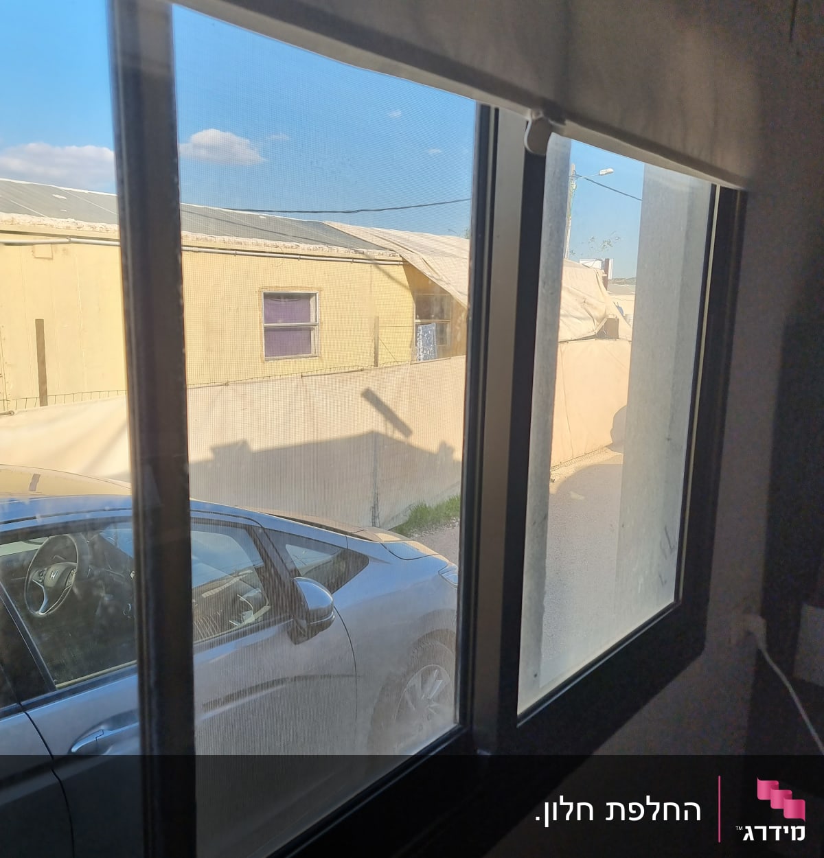 חלון זכוכית עם נוף חיצוני של רכב ובניין